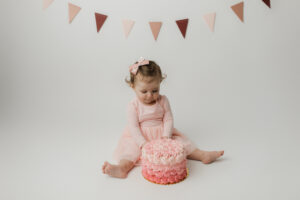 baby girl in pink eating cake