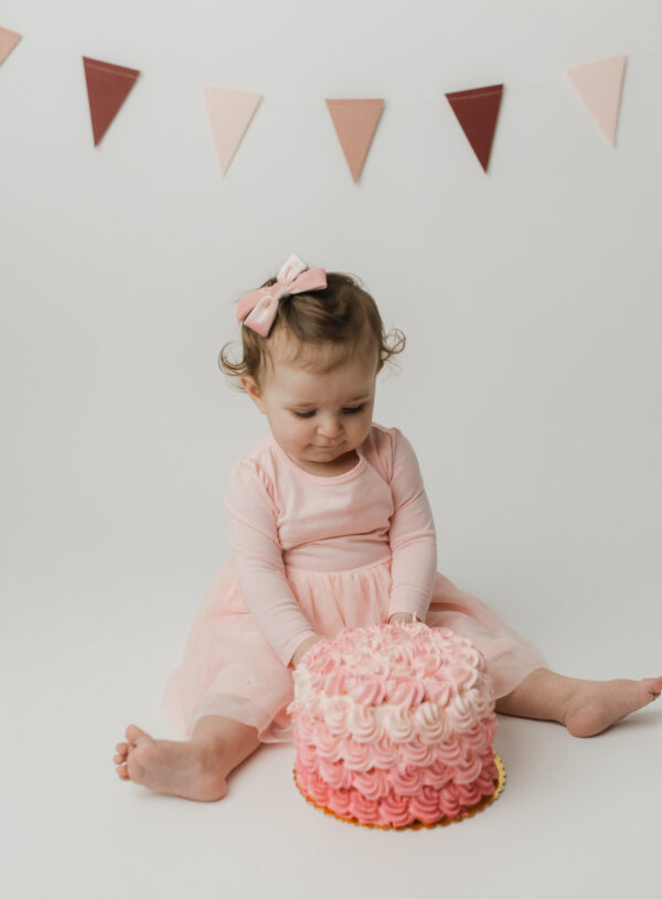 baby girl in pink eating cake