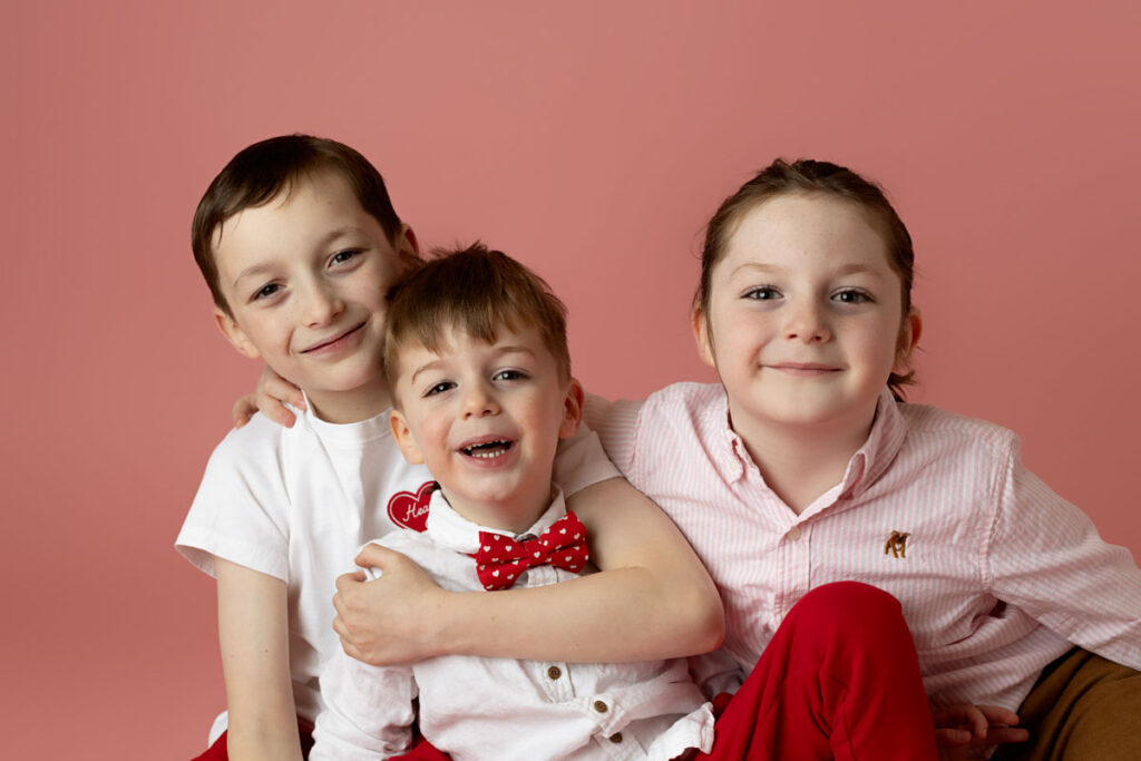 brothers smiling on a pink backdrop