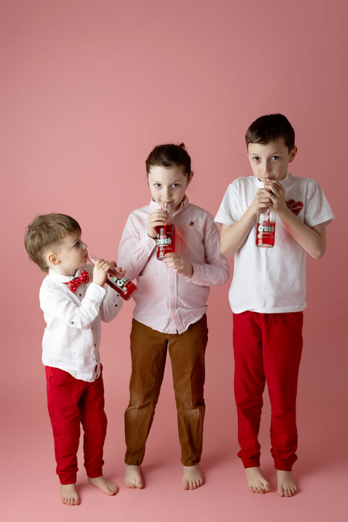 boys drinking soda on a pink backdrop