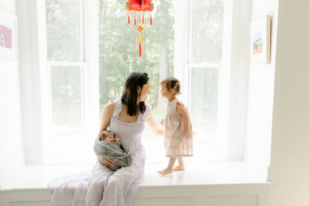 a mom and 2 girls sitting on a window seat