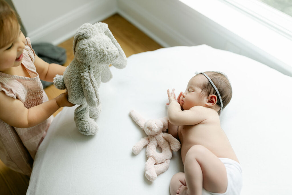 sibling giving a stuffie to her newborn sister