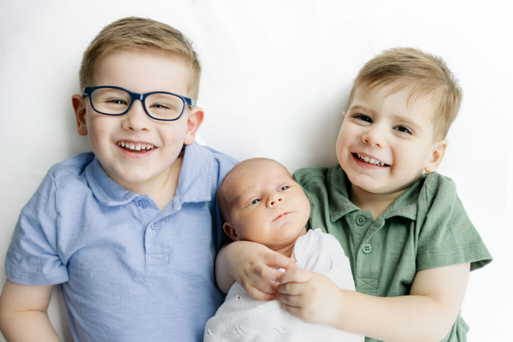 2 boys lying down with their baby brother