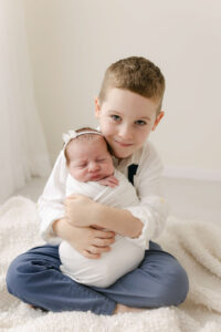 5 year old boy sibling holding his newborn sister